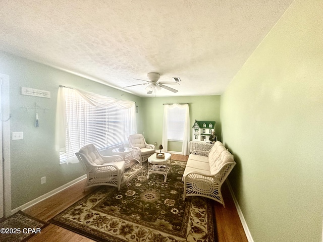 sitting room with wood-type flooring, ceiling fan, and a textured ceiling