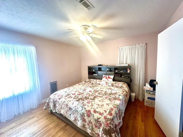 bedroom with ceiling fan, hardwood / wood-style floors, and a textured ceiling