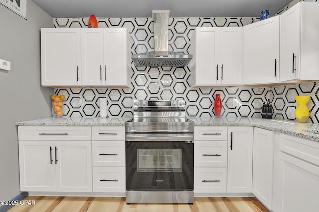 kitchen with light stone counters, electric range, exhaust hood, and white cabinets