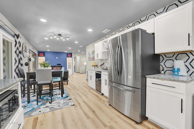 kitchen featuring light stone counters, stainless steel appliances, beverage cooler, and white cabinets