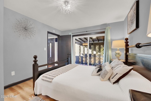 bedroom featuring hardwood / wood-style flooring, access to exterior, and a notable chandelier