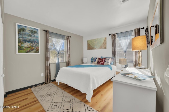 bedroom with multiple windows and hardwood / wood-style flooring