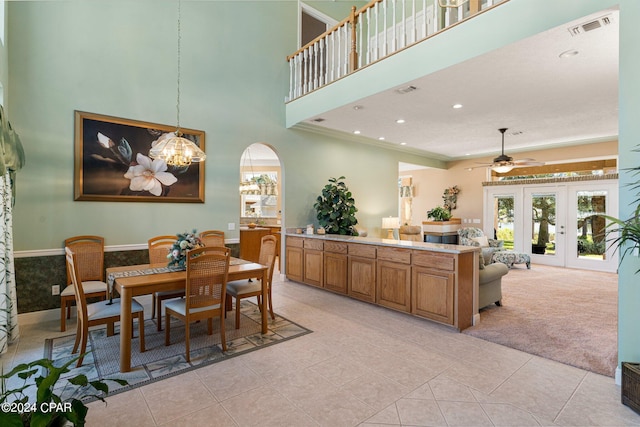 dining area with crown molding, ceiling fan with notable chandelier, light tile patterned floors, and french doors