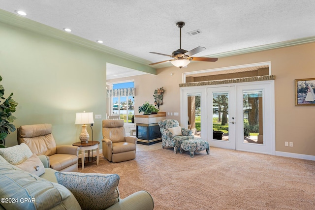 carpeted living room featuring plenty of natural light, a textured ceiling, ornamental molding, and french doors