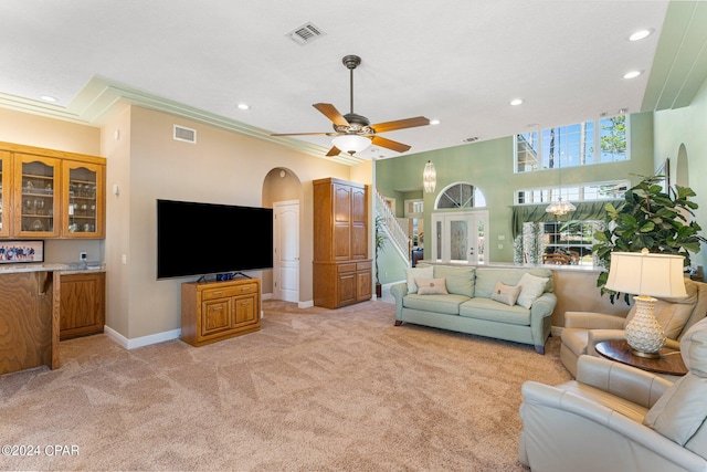 carpeted living room with ceiling fan and ornamental molding