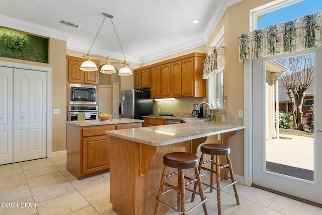 kitchen with kitchen peninsula, hanging light fixtures, appliances with stainless steel finishes, sink, and light tile patterned floors