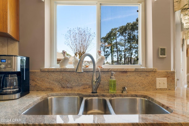 kitchen featuring light stone countertops, sink, a wealth of natural light, and decorative backsplash