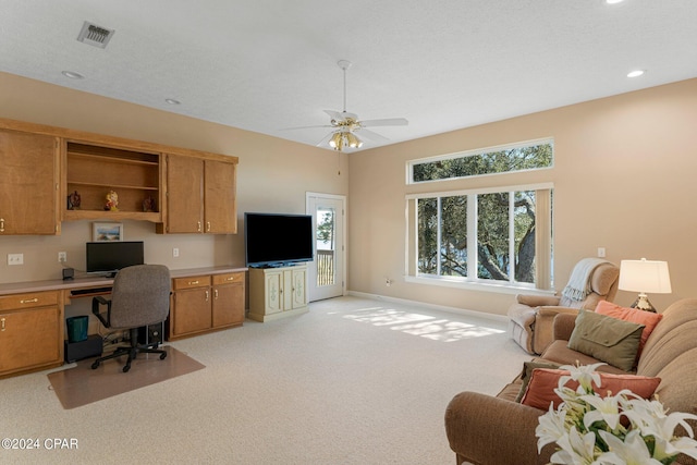 home office featuring ceiling fan, light carpet, built in desk, and a healthy amount of sunlight