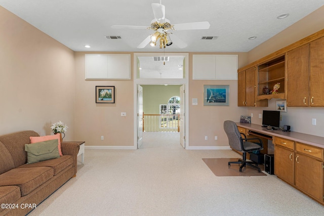 carpeted home office with ceiling fan and built in desk