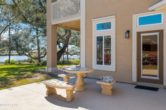 property entrance featuring a lawn, a patio area, and a water view