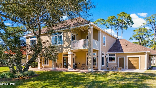 back of house with a balcony, a patio area, a garage, and a lawn