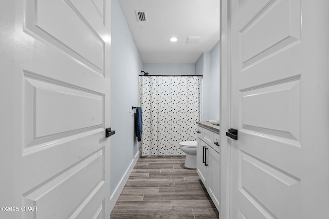 bathroom featuring wood-type flooring, curtained shower, vanity, and toilet