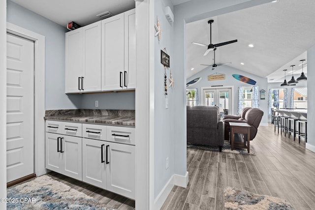 kitchen with white cabinetry, lofted ceiling, and light wood-type flooring