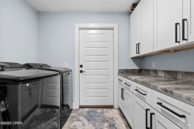 laundry area featuring cabinets, washing machine and dryer, and wood-type flooring