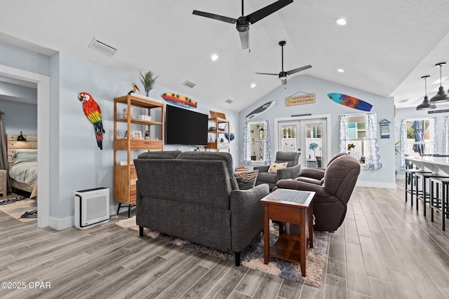 living room featuring ceiling fan, vaulted ceiling, french doors, and a healthy amount of sunlight