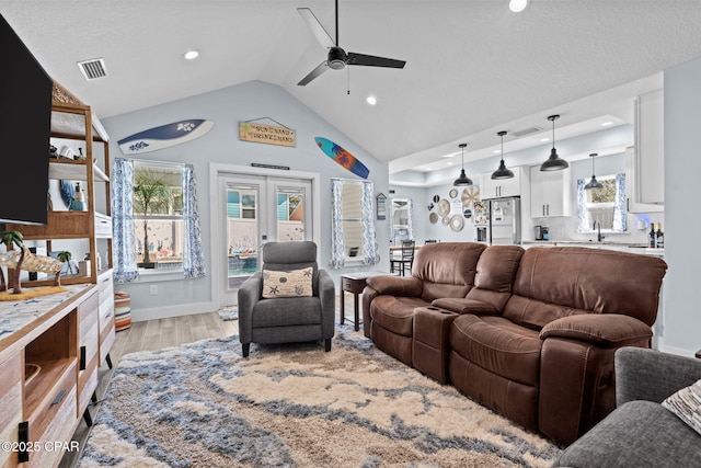 living room with lofted ceiling, sink, light hardwood / wood-style flooring, ceiling fan, and french doors