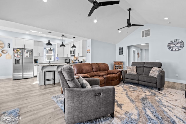 living room featuring high vaulted ceiling, sink, ceiling fan, and light hardwood / wood-style flooring