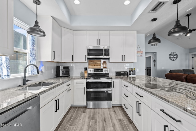 kitchen featuring sink, white cabinetry, hanging light fixtures, light hardwood / wood-style flooring, and stainless steel appliances