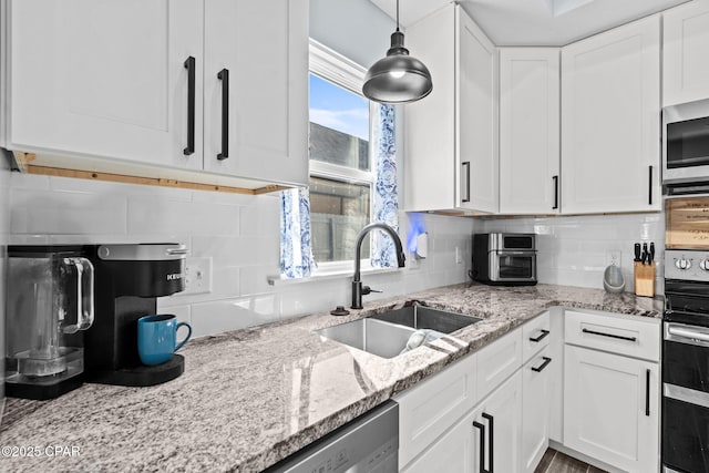 kitchen featuring white cabinetry, appliances with stainless steel finishes, decorative light fixtures, and sink