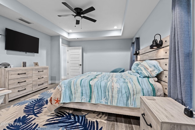 bedroom featuring a raised ceiling, ceiling fan, and light wood-type flooring