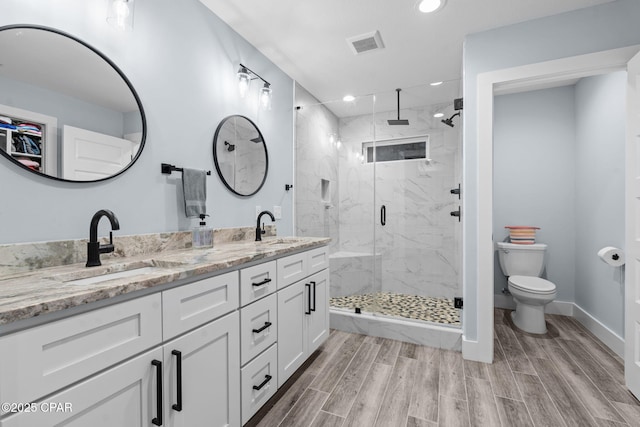 bathroom with walk in shower, vanity, and toilet