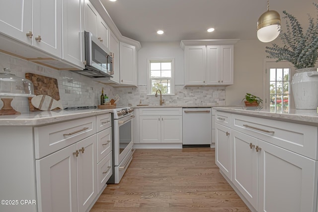 kitchen featuring sink, white cabinetry, tasteful backsplash, white appliances, and light hardwood / wood-style floors