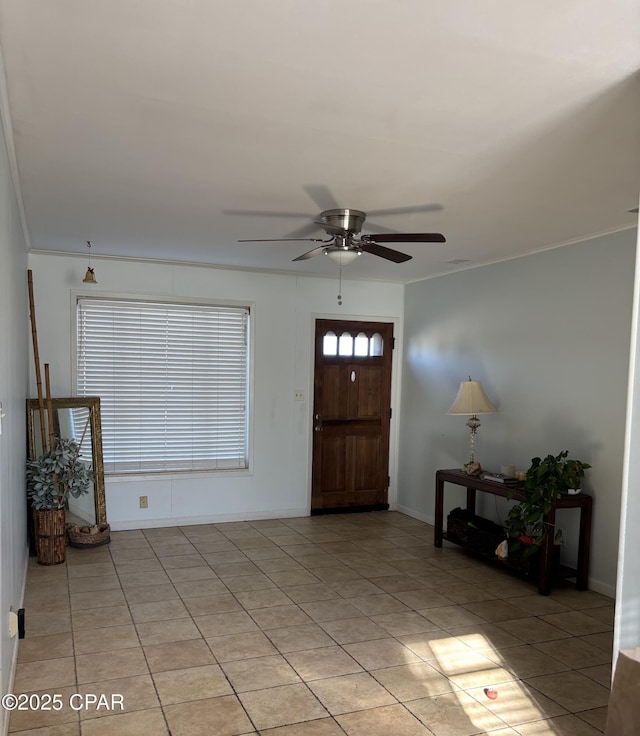 tiled entrance foyer featuring crown molding and ceiling fan