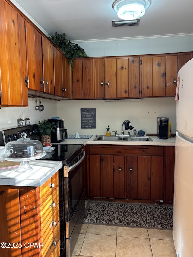 kitchen featuring sink, electric range, light tile patterned floors, and white refrigerator