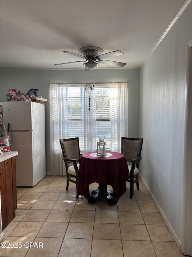 tiled dining space featuring crown molding and ceiling fan