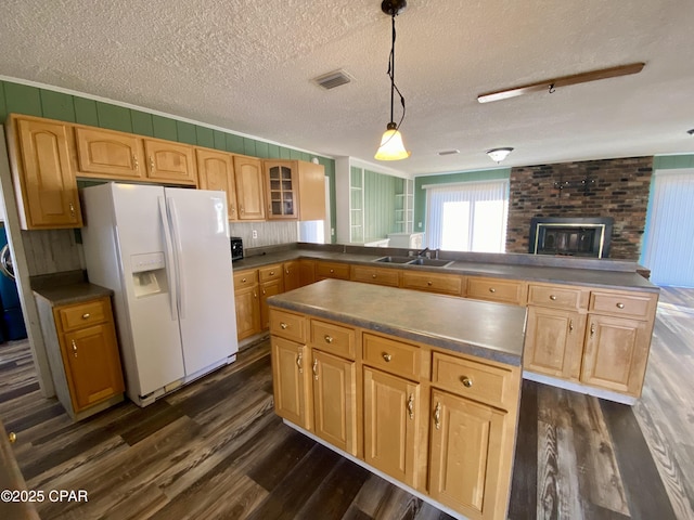 kitchen featuring hanging light fixtures, sink, white fridge with ice dispenser, and kitchen peninsula