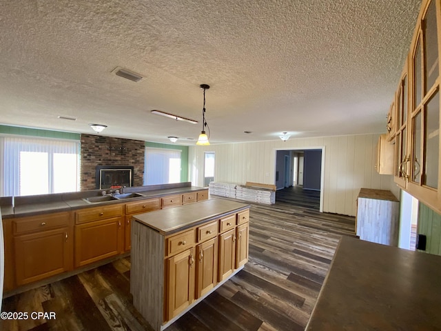 kitchen with decorative light fixtures, sink, a kitchen island, and a wealth of natural light