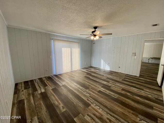 empty room with ceiling fan, ornamental molding, dark hardwood / wood-style flooring, and a textured ceiling