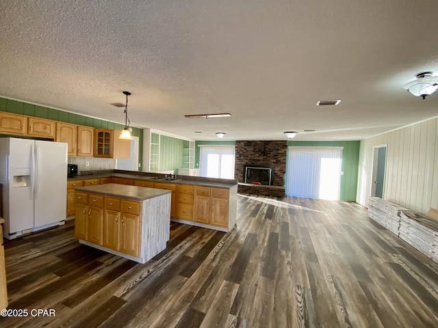 kitchen featuring pendant lighting, sink, dark wood-type flooring, white fridge with ice dispenser, and a kitchen island