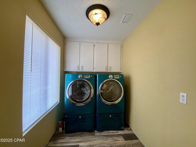 clothes washing area featuring cabinets, a wealth of natural light, washer and dryer, and a textured ceiling