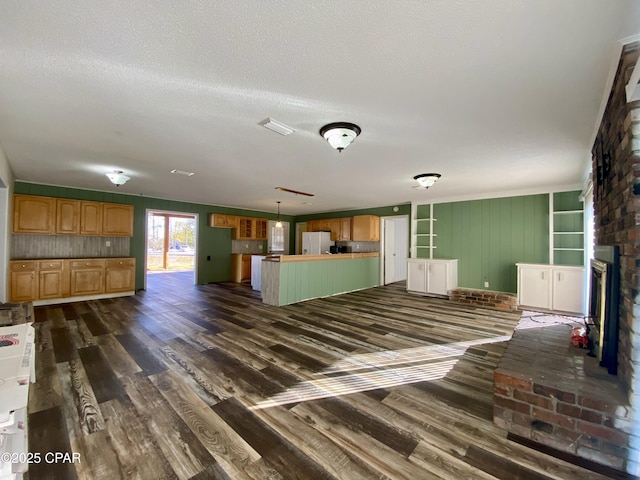 unfurnished living room featuring a brick fireplace, dark hardwood / wood-style floors, and a textured ceiling