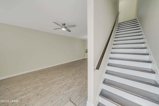 stairs featuring hardwood / wood-style floors and ceiling fan