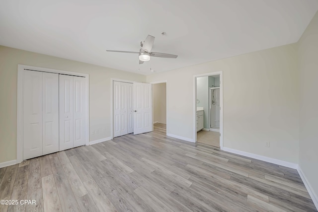 unfurnished bedroom with multiple closets, light wood-type flooring, ceiling fan, and ensuite bath