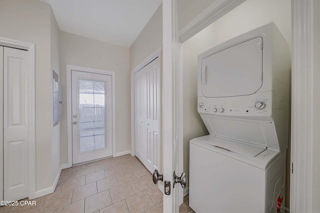 laundry room featuring stacked washer and dryer and light tile patterned floors