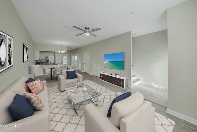 living room featuring ceiling fan with notable chandelier and light hardwood / wood-style floors