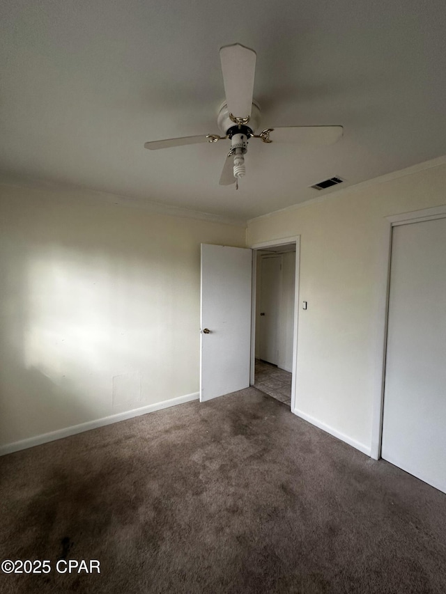 unfurnished bedroom featuring carpet, crown molding, visible vents, a ceiling fan, and baseboards