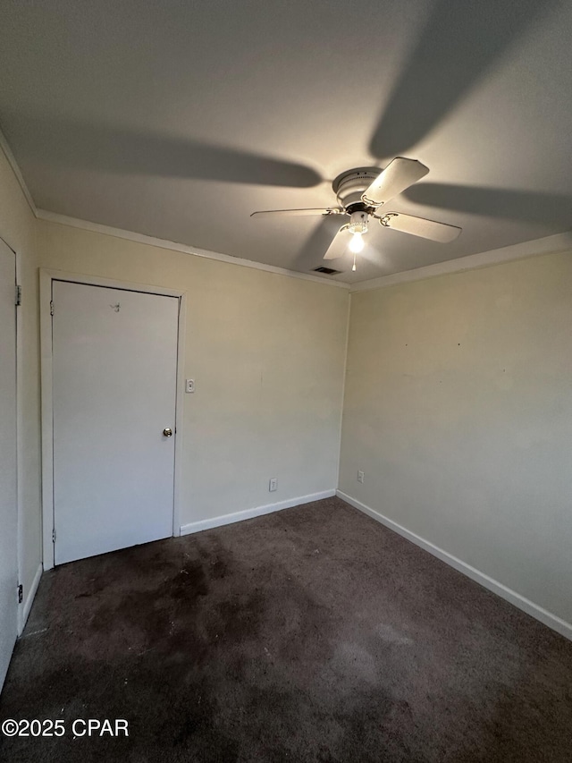 spare room featuring visible vents, baseboards, a ceiling fan, ornamental molding, and dark carpet