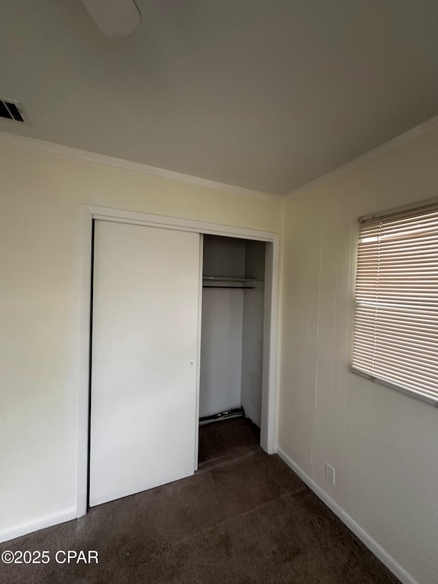 unfurnished bedroom featuring crown molding, visible vents, and a closet