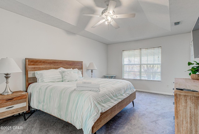 carpeted bedroom with ceiling fan, a raised ceiling, visible vents, and baseboards