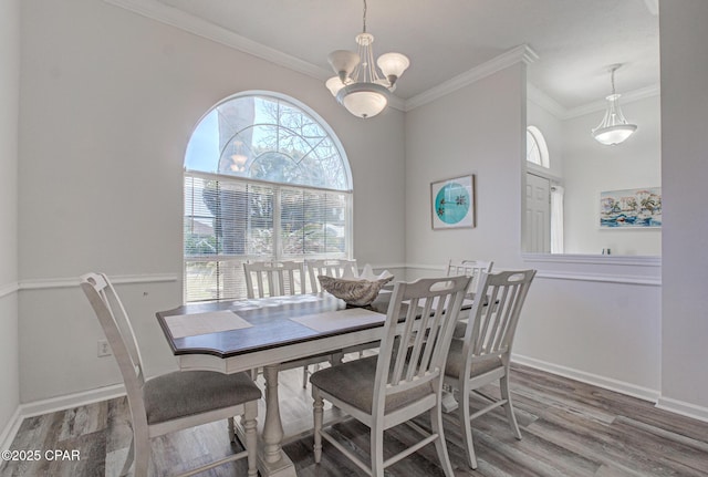 dining space with baseboards, ornamental molding, wood finished floors, and an inviting chandelier