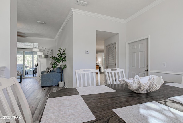 dining space featuring visible vents, crown molding, and wood finished floors