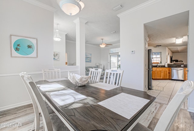 dining space featuring light wood finished floors, decorative columns, visible vents, ceiling fan, and ornamental molding