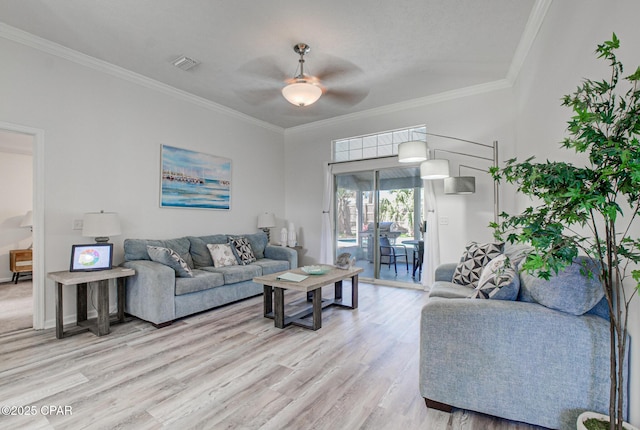 living area with visible vents, ornamental molding, light wood-style floors, baseboards, and ceiling fan