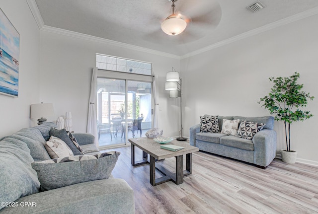 living room with visible vents, a ceiling fan, wood finished floors, crown molding, and baseboards