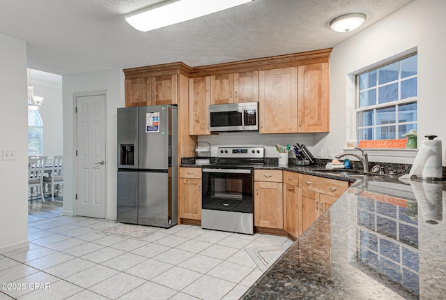 kitchen with light tile patterned floors, stainless steel appliances, a sink, a textured ceiling, and plenty of natural light