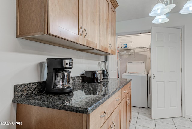 kitchen with light tile patterned floors, washer and dryer, and dark stone countertops